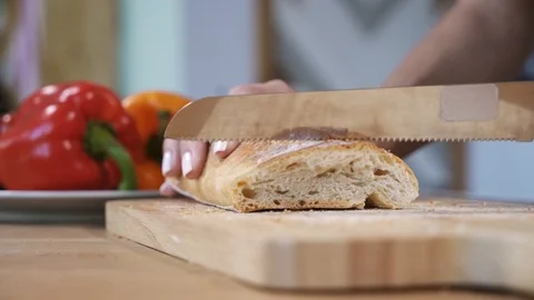 Hands of woman cutting bread on table with bell peppers Video stock 100031263