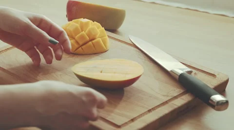 Hands of a woman opening a mango slice on a chopping board 4K Stock Footage 61751932