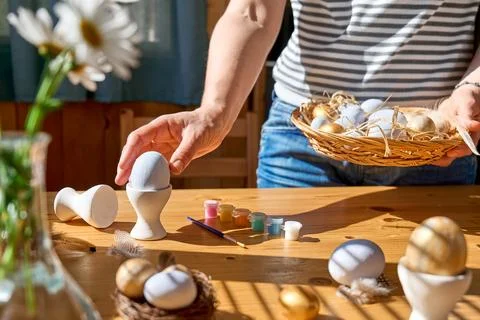 Hands of woman preparing easter decoration at home, holding basket with color Stock Photos