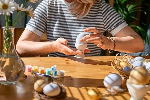 Hands of woman preparing easter decoration at home, putting colorful easter.. Stock Photos