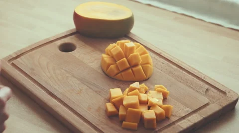 Hands of a woman segmenting mango on a chopping board in the kitchen 4K Stock Footage 61754702