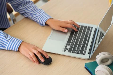 Hands of woman using computer mouse and laptop at table in office Stock Photos
