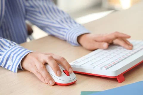 Hands of woman using computer mouse and keyboard at table in office Stock Photos