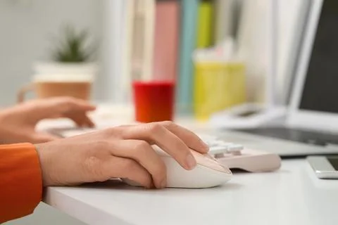 Hands of woman using computer mouse and keyboard at table in office Stock Photos