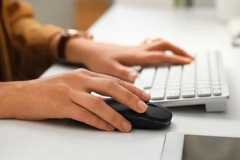 Hands of woman using computer mouse and keyboard at table in office Stock Photos