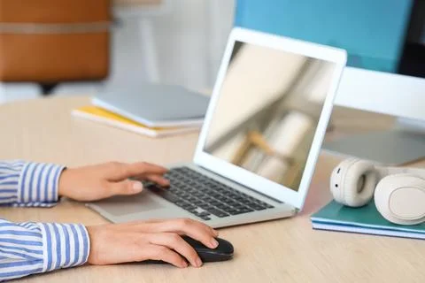 Hands of woman using computer mouse and laptop at table in office Stock Photos