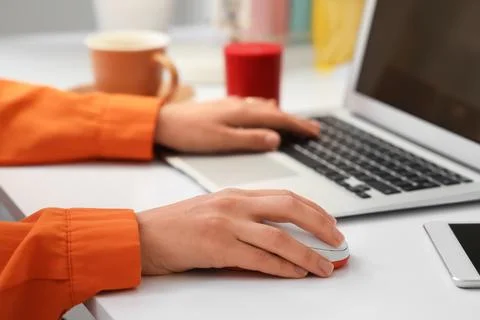 Hands of woman using computer mouse and laptop at table in office Stock Photos