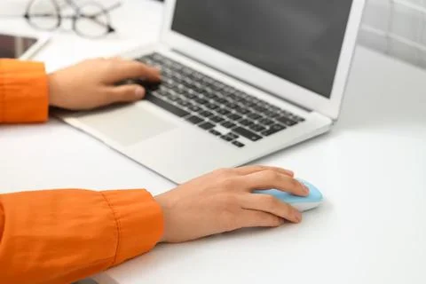 Hands of woman using computer mouse and laptop at table in office Stock Photos