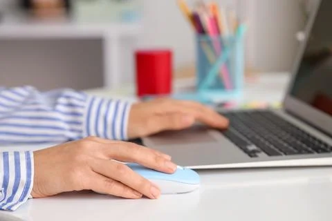 Hands of woman using computer mouse and laptop at table in office Stock Photos