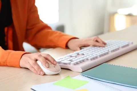 Hands of woman using computer mouse and keyboard at table in office Stock Photos