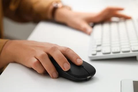 Hands of woman using computer mouse and keyboard at table in office Stock Photos