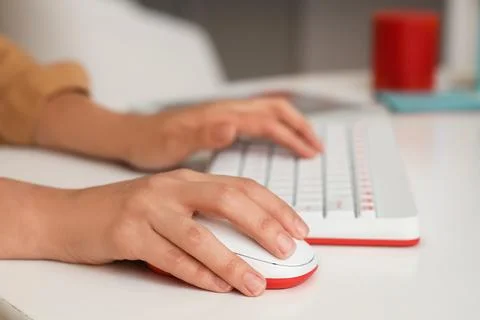Hands of woman using computer mouse and keyboard at table in office Stock Photos