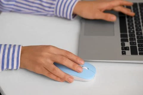 Hands of woman using computer mouse and laptop at table in office Stock Photos