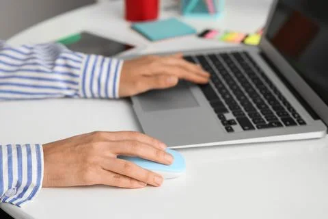 Hands of woman using computer mouse and laptop at table in office Stock Photos