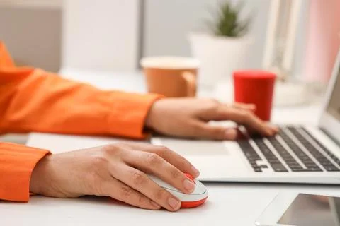 Hands of woman using computer mouse and laptop at table in office Stock Photos