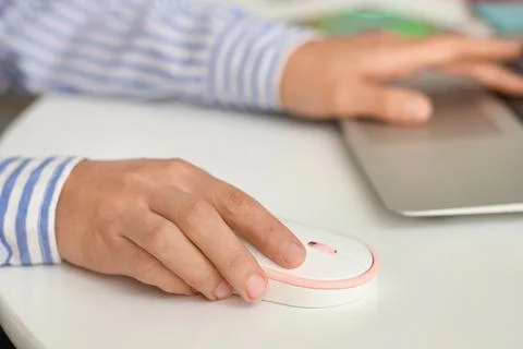 Hands of woman using computer mouse and laptop at table in office Stock Photos