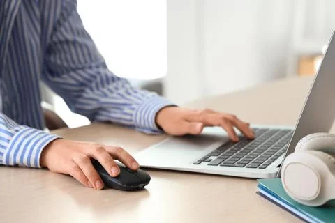 Hands of woman using computer mouse and laptop at table in office Stock Photos