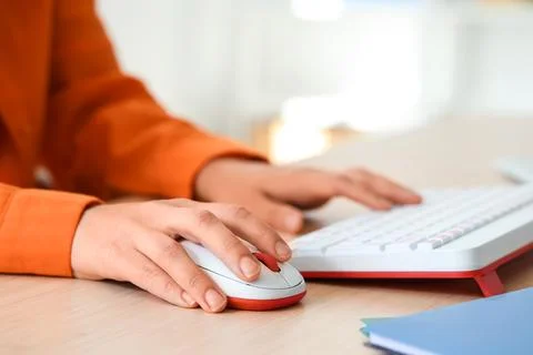 Hands of woman using computer mouse and keyboard at table in office Stock Photos
