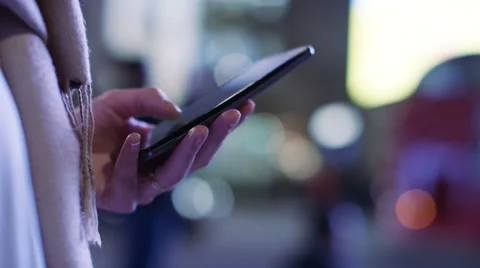 Hands of a woman using her cell phone at night in the city, in slow motion Video stock 58594810
