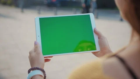 Hands woman using tablet device computer with green screen outdoors in street at Stock Footage 116440834