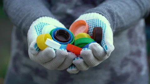Hands in work gloves hold a lot of plastic caps. Street cleaning from plastic Stock Footage 204812571