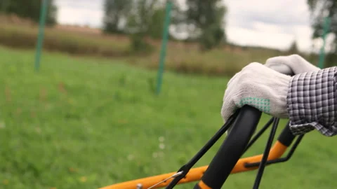 Hands in work gloves pushing a lawn mower. Stock Footage 317677590