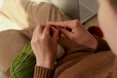 Hands work on a knitted piece while holding yarn and knitting needles. The 스톡 동영상 336464889