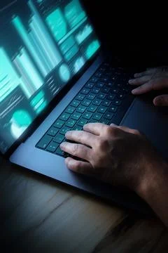 Hands work on laptop displaying data at night in a dark space 写真素材