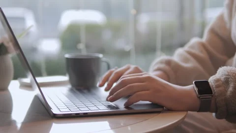 Hands work on laptop near window with cup nearby Stock Footage 342018878