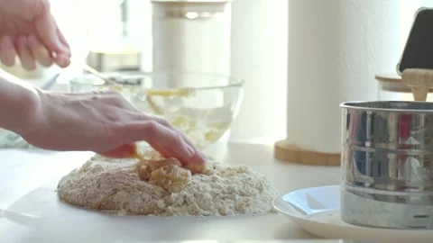 Hands work sticky dough with flour on kitchen counter beside sifter and bowl Stock Footage 334683339