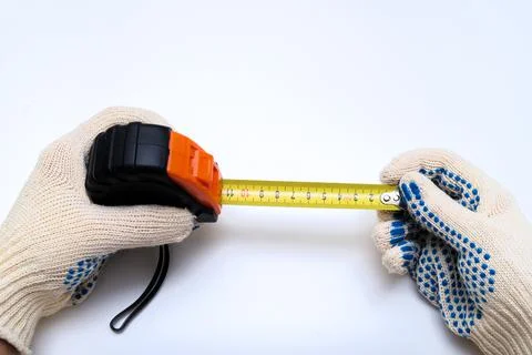 Hands of a worker, builder in protective gloves halding a ruler, using tape Stock Photos