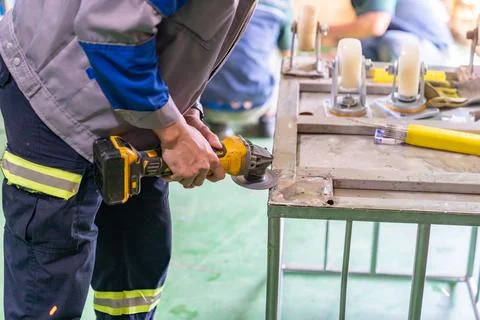 Hands of worker grinding a cart base wheel for install. Stock Photos