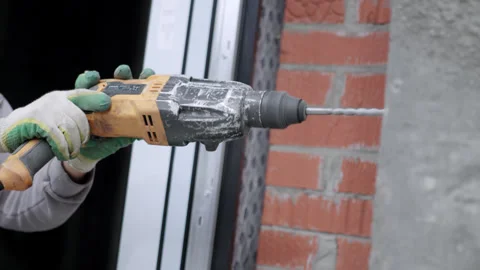 Hands of worker hold drill while penetrating solid wall Stock Footage 330070675