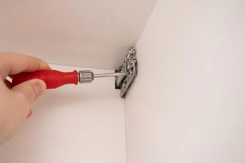 Hands of a worker installing a Fasteners for kitchen drawers to the wall. Fotos de archivo