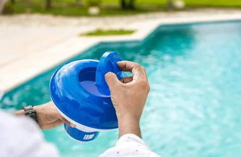 Hands of a worker installing a pool chlorine float, a person holding a poo... 스톡 사진
