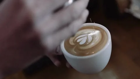 Hands of a worker making a cappuccino latte art in a cup at a coffee shop. Stock-Footage 334648372