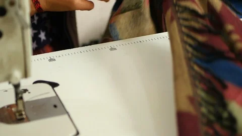 Hands of worker in Nepal pulling fabric along table next to sewing machine Video stock 119340531