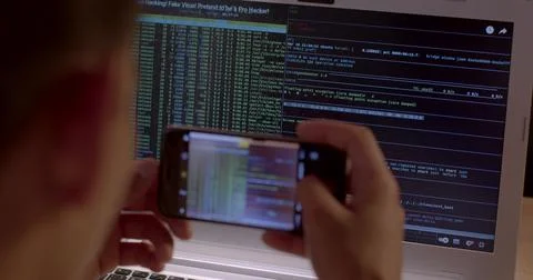 Hands worker take photos of the programming code from a laptop monitor. Stock Photos