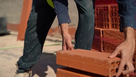 Hands of a worker taking bricks from a pallet and stacking them on the grou.. Stock Footage 242036439