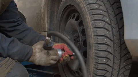 Hands of the worker twisting bolts on car wheel. Stock Footage 129379627
