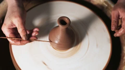 Hands working clay on potter's wheel. Potter draws a drawing with a stick on the Video stock 144073695