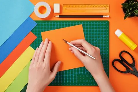 Hands working with colorful paper using a precision knife on a green cuttin.. Stock Photos