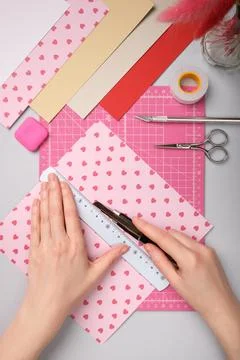Hands working with colorful paper using a precision knife on pink cutting m.. Stock Photos