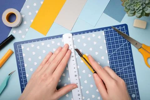 Hands working with colorful paper using a precision knife on blue cutting mat Stock Photos