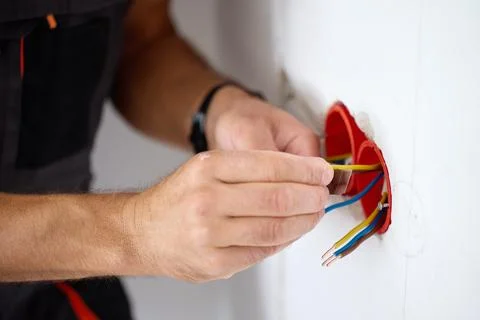 Hands working with electrical wires inside a wall Stock Photos
