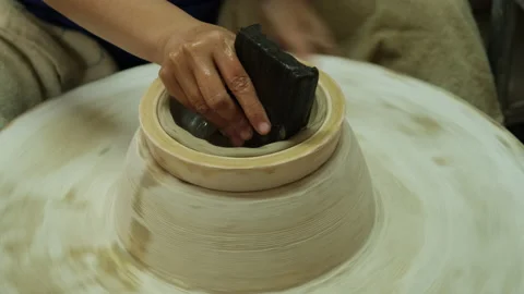 Hands working on a potter's wheel making clay objects in pottery workshop. Stock Footage 194530973