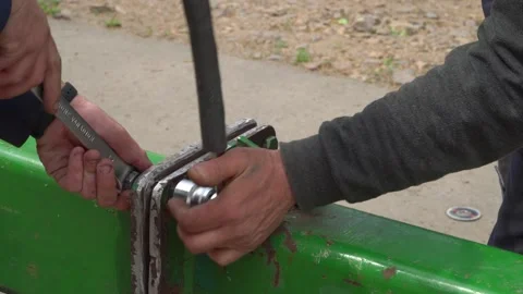 Hands Working with Various Tools on a Green Machinery Component for Repair Stock Footage 295920531