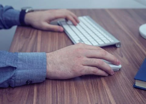 Hands working with wireless keyboard and mouse on wooden table Stock Photos