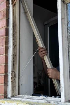 Hands of workman pulling old wooden window frame from brick wall Stock Photos