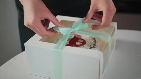 Hands wrap a gift box with cake inside Vídeo Stock 336049563